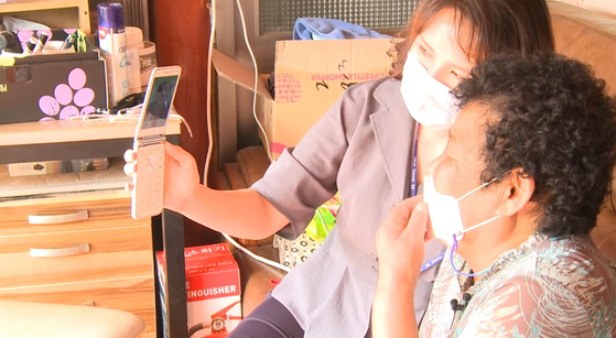 An elderly woman speaks over video call with her family with the help of a public official during last year's Chuseok harvest festival in Wando, South Jeolla. [JOONGANG PHOTO] 