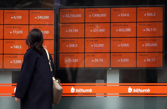 A passerby looks at cryptocurrency prices displayed through a screen operated by local crytocurrency exchange Bithumb in Gangnam, southern Seoul, on Monday. [YONHAP]