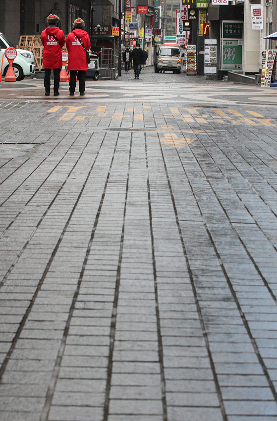 Seoul city government tour guides wait for tourists on the empty streets of Myeong-dong on Tuesday. As the Covid-19 pandemic rages on, once popular destinations such as Myeong-dong have been hit hard. [YONHAP] 