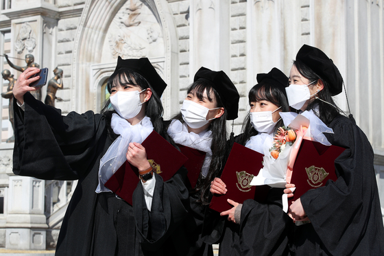 College students of Kyung Hee University in Seoul take selfies on campus to celebrate their graduation on Wednesday. The university did not hold a ceremony and instead designated the week from Feb. 17 until Feb. 24 as "graduation week" to allow graduates to individually celebrate. [JANG JIN-YOUNG]