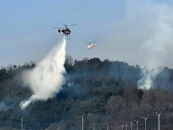 Firefighting helicopters extinguish flames at a wildfire site in Andong, North Gyeongsang on Monday. The fire forced 108 residents in the area to evacuate on Sunday afternoon and evening. [YONHAP]
