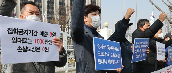 Small shop owners, including those who own indoor gyms, demand the government create a measure that would compensate for losses incurred due to the strict social distancing rather than a universal emergency relief grant in front of the government complex in Seoul on Feb. 22. [YONHAP]