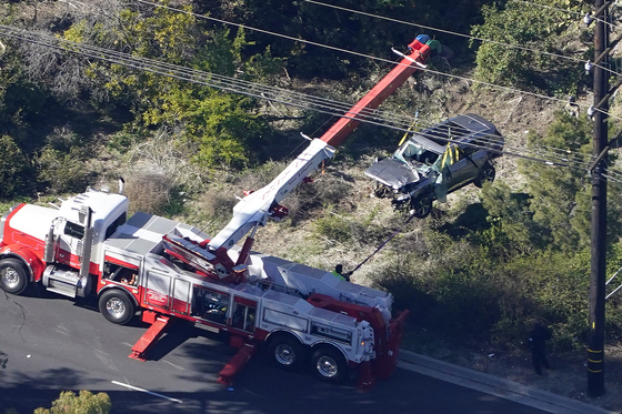 Workers move a vehicle after a rollover accident involving golfer Tiger Woods on Tuesday in Rancho Palos Verdes, Calif., a suburb of Los Angeles.. Woods suffered leg injuries in the one-car accident and was undergoing surgery, authorities and his manager said. [AP]