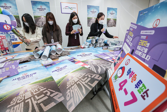 Officials from the Seoul branch of the National Election Commission on Wednesday examine posters to encourage voters to cast their ballots in the by-election for Seoul mayor on April 7. [YONHAP]