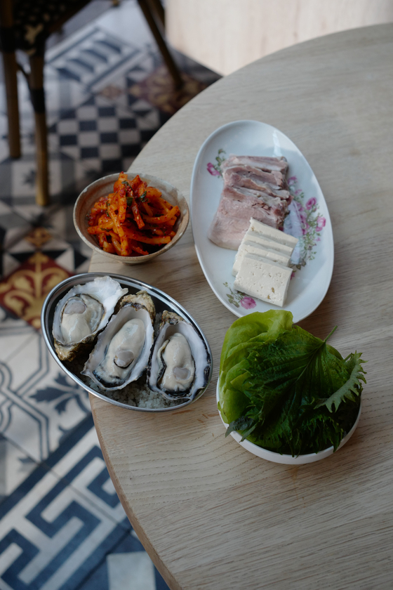 Bossam, or steamed pork, comes with many different sides to eat together, such as oyster, and radish seasoned with gochugaru. [AGENCE NEROLI]