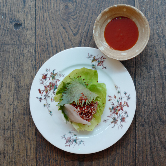 Yukhoe, Korean style beef tartar is seasoned with sesame oil and gochugaru, hot pepper flakes. Just like Koreans often pair pear with the dish, the restaurant also serves the raw meat with pear and some sesame leaves. [AGENCE NEROLI]