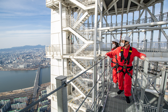 Models look at city below from Lotte World Tower’s sky bridge in Seoul. According to Lotte, starting March 5, it will reopen its sky bridge tour, which was closed for the winter. The sky bridge tour program kicked off in July last year. [YONHAP]