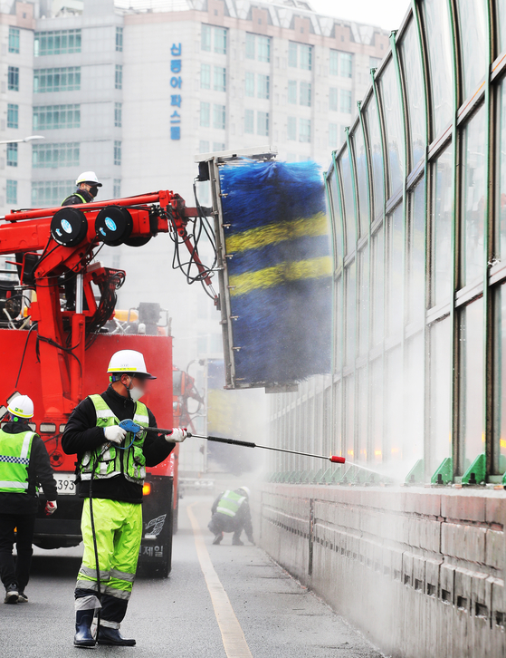 Janitors clean noise barriers on an overpass in Suwon, Gyeonggi, on Thursday. [YONHAP]