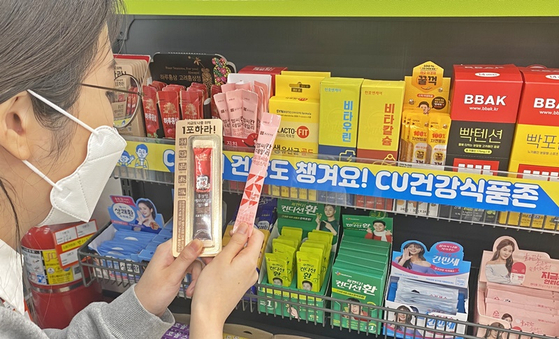 A woman shops for health supplements packaged in sachets at a CU. [BGF RETAIL]