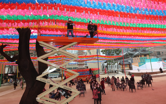 Workers hang lotus lanterns over the yard of Jogye Temple in Jongno District, central Seoul, on Monday. The colorful lanterns are in celebration of Buddha’s birthday which falls on May 19 this year. [YONHAP]
