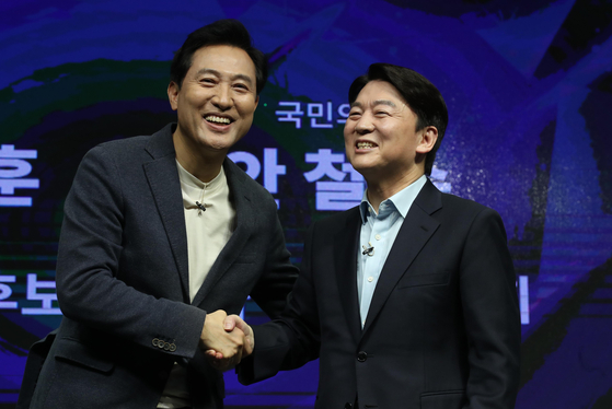 Seoul mayoral candidates Oh Se-hoon, left, of the People Power Party and Ahn Cheol-soo of the People's Party shake hands after announcing their visions for the opposition parties' plan to field a consolidated candidate in the April 7 Seoul mayoral by-election on Monday. [YONHAP]