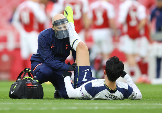 Tottenham Hotspur's Son Heung-min receives medical attention after sustaining an injury against Arsenal at Emirates Stadium in London on Sunday. [REUTERS/YONHAP]