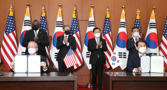 Jeong Eun-bo, right, Korea’s top negotiator for the defense cost-sharing negotiations, and Rob Rapson, the acting U.S. ambassador to Seoul, initial the Special Measures Agreement at a signing ceremony at the Foreign Ministry in central Seoul Thursday. U.S. Defense Secretary Lloyd Austin and Secretary of State Antony Blinken and Korea’s Foreign Minister Chung Eui-yong and Defense Minister Suh Wook watch on after their two-plus-two meeting. [JOINT PRESS CORPS]