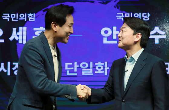 Oh Se-hoon and Ahn Cheol-soo shake hands on March 15 at a television studio in Yeongdeungpo District, Seoul after announcing their intent to support a single candidate in the Seoul mayoral by-election. [NEWS1]