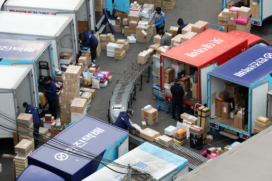 Delivery workers sort packages at a logistics facility in Seoul. [NEWS1]