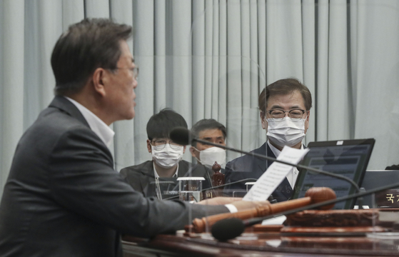 Suh Hoon, right, director of the National Security Office, listens to President Moon Jae-in at an interagency meeting at the Blue House Tuesday. Suh departed Wednesday for a trilateral meeting with his U.S. and Japanese counterparts Friday in the United States. [JOINT PRESS CORPS]