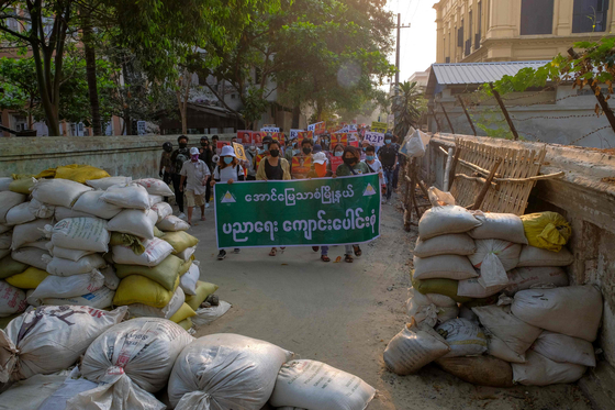 This photo received from an anonymous source via Facebook on April 1, 2021 shows protesters walking towards makeshift barricades while taking part in a demonstration against the military coup in Mandalay. [AFP]