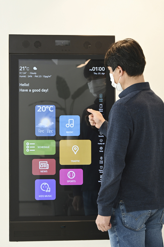 An LG Electronics employee demonstrates its Smart Mirror, which activates a KT platform that provides radio, music and other digital services. According to LG Electronics and KT on Tuesday, the two will work on developing cross-platform services. [LG ELECTRONICS, KT]