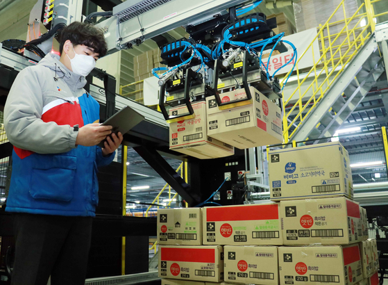 A CJ Logistics employee operates robotic arms to move around boxes at one of the logistics company's warehouses. The company on Thursday announced the commercial use of the artificial intelligence-operated robotic system in its conveyor line. [CJ LOGISTICS] 