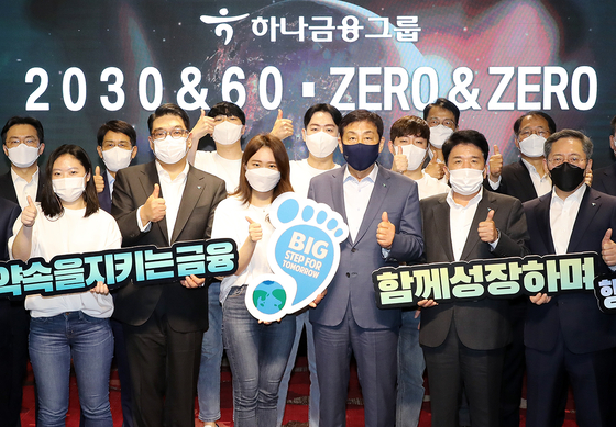 Hana Financial Group Chairman Kim Jung-tai, third from right in front, poses with group officials during an event held Thursday to announce the group's vision to achieve carbon neutrality by 2050 at H-Pulse, a lounge operated by Hana Bank for members of the group's loyalty program, Hana Members, in Mapo District, western Seoul. [HANA FINANCIAL GROUP] 