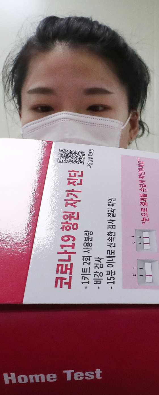 An employee goes through a final inspection of SD Biosensor's Covid-19 home-test kit on Thursday at the biotech firm's factory before the kits are sold in pharmacies and online stores. The home-test kits, approved by the World Health Organization (WHO), use reverse transcription PCR (RT-PCR) technology. Users can use a cotton swab to collect samples from their nose and dip it into a solution, with results coming out within 15 to 30 minutes. [YONHAP]