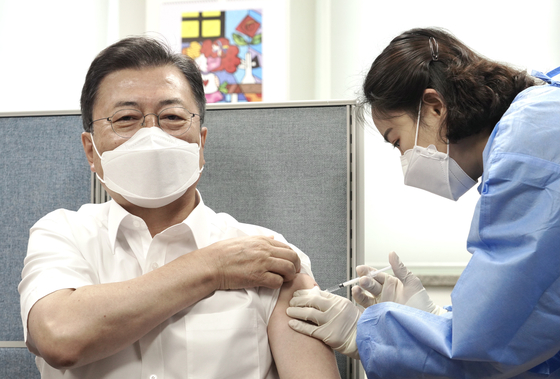 President Moon Jae-in, left, receives the second dose of the Covid-19 vaccine at the Jongno District Public Health Center on Friday. He received the second doze of the AstraZeneca vaccine earlier than scheduled in order to visit Washington for his summit with U.S. President Joe Biden on May 21. [YONHAP]