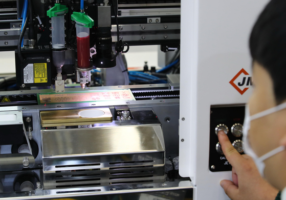 A staff from a chip equipment company demonstrates a laser printer at the annual Semiconductor Exhibition held in October at COEX, southern Seoul. [YONHAP]