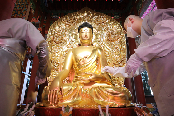 Monks clean a statue of Buddha in the main hall of Jogye Temple in Jongno District, central Seoul, on Tuesday, a week ahead of Buddha’s Birthday on May 19 this year. [NEWS1]