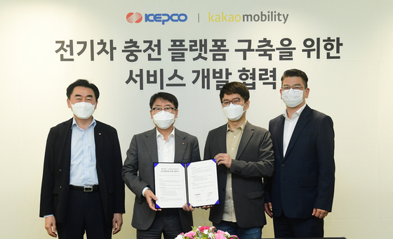 Lee Jong-hwan, Kepco Vice President. second from left, and Alex Ryu, Kakao Mobility CEO, second from right, hold up a signed MOU at Kakao Mobiilty's headquarters in Seongnam, Gyeonggi, on Friday. [KEPCO]  