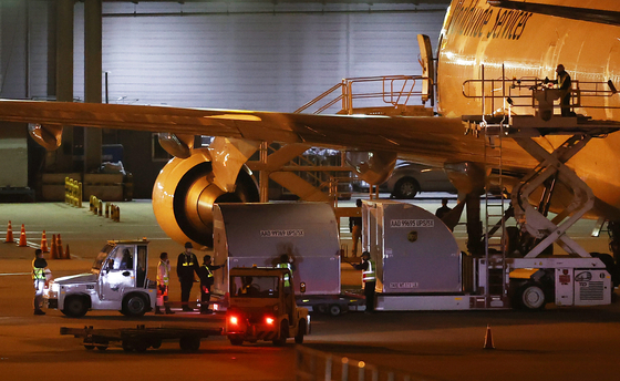 Officials unload containers carrying 438,000 doses of Pfizer Covid-19 vaccines from a UPS cargo plane that landed at Incheon International Airport on Wednesday.