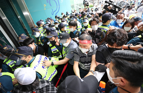 Owners of entertainment establishments, such as hostess bars and noraebang (singing rooms), clash with police on Thursday while attempting to storm into Seoul City Hall, demanding a ban, levied on their businesses because of fears of Covid-19 infection, be lifted. [YONHAP]
