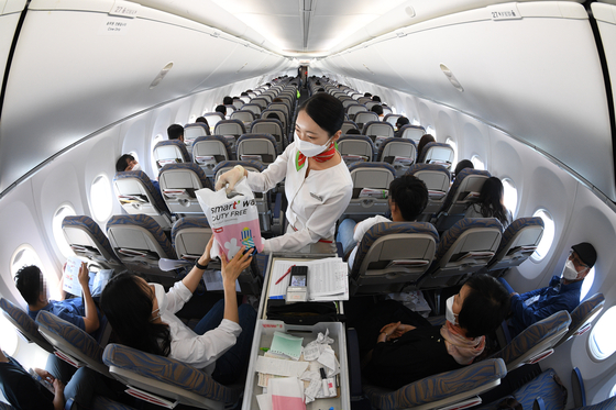 A T’way Air flight attendant handing duty-free purchases to a passenger on a flight to nowhere, that takes off and lands back where it started without an intermediate stop, between Daegu and Fukuoka, Japan. The budget airliner said Sunday that it has started its inflight duty-free shopping for customers getting on from the Daegu International Airport. [YONHAP]