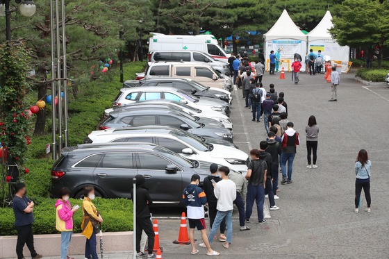 Citizens wait in line to get tested for Covid-19 at a temporary screening center in Daegu on Sunday. Infections tied to adult entertainment facilities are quickly increasing in the city, with 179 cases so far. [NEWS1]