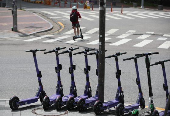 E-scooters parked around Hongik University in western Seoul on Tuesday. The once-popular ride has lost many users since tough restrictions, requiring a drivers license and helmet and banning more than one person from riding on the same scooter, were implemented from May 13.  [YONHAP] 