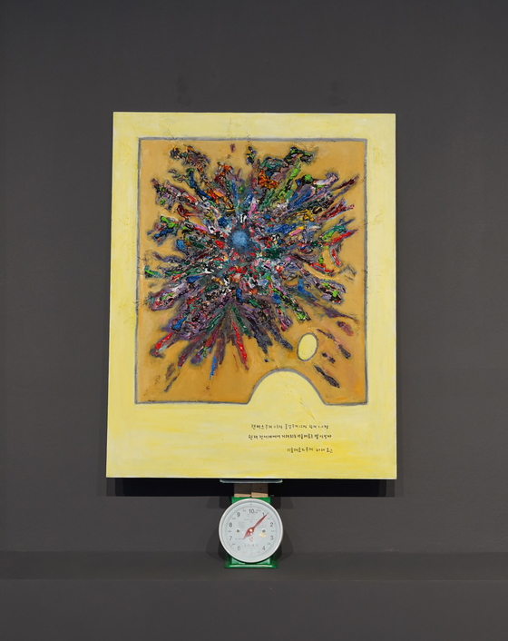 Joo Jae-hwan's ″Weight of Materials for Art″ is a mixed-media artwork where his painting is being weighed on a scale to symbolize how the art market only relies on subjective interpretations of an artwork and not the quantitative properties such as the weight of the painting or the weight of the paint used in an artwork. [JEON TAE-GYU]