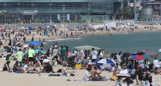Tourists and locals cool off at Haeundae Beach in Busan on Sunday. As summer is coming, local governments announced plans to fully open beaches in July. Until then, some of the most popular beaches, like Haeundae Beach, will limit the number of people when they partially open this Tuesday. [SONG BONG-GEUN]