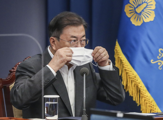 President Moon Jae-in puts on a mask after finishing his speech at a meeting with his aides at the Blue House on May 17 [KIM SEONG-RYONG]