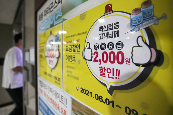 A sign at a sauna in Seoul offering a 2,000 won ($1.80) discount to visitors who have received the coronavirus vaccine on Sunday. Many companies, including restaurants and saunas, are coming up with various discount promotions targeting customers who are ready to go outdoors after getting vaccinated. [YONHAP]