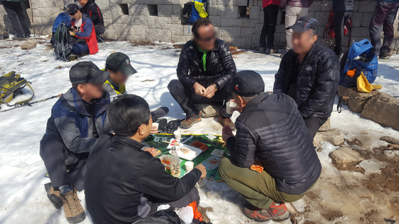A group of hikers are drinking makeolli near the Daedongmun Gate at Mt. Bukhansan in March 2018. [KOREA NATIONAL PARK] 