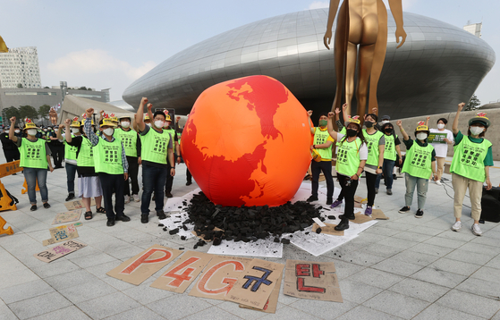 Civic group members stage a performance to raise awareness of carbon emissions by displaying a burning earth structure in front of Dongdaemun Design Plaza in central Seoul on Monday, where the P4G Summit was held. [YONHAP]