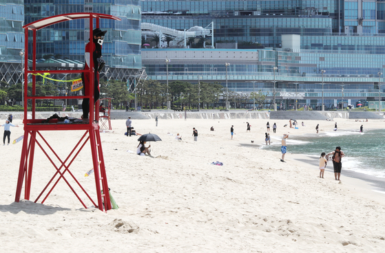 A lifeguard stands in a lookout tower at Haeundae Beach in Busan on Monday, after the beach pre-opened with quarantine measures taken amid the coronavirus pandemic. Haeundae and Songjeong beaches reopened on June 1, and no parasols or tubes will be provided during the month due to Covid-19. [YONHAP]