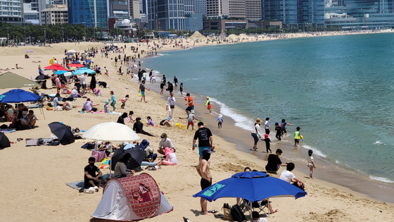 People enjoy the beach at Haeundae, Busan, on May 30 as the warm weather attracted beachgoers. Online travel, leisure and cultural purchases rose sharply in April. [YONHAP] 