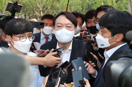 Former Prosecutor General Yoon Seok-youl is asked questions by reporters as he makes his way to the opening of the Woodang Memorial Hall in central Seoul on Wednesday. [YONHAP]
