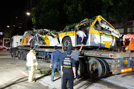 Police move a city bus, destroyed by a collapsed building in Gwangju, on Thursday. Nine passengers on the bus were killed and eight others were seriously inured when a building collapsed and fell on top of it on Wednesday.  [YONHAP] 