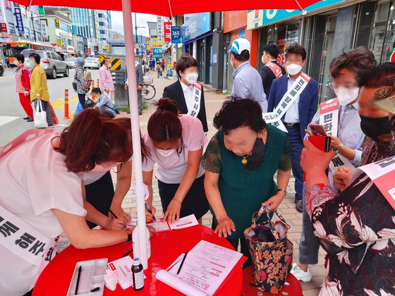 In this photo provided by Rep. Chung JIn-suk of the People Power Party on Wednesday, residents of Gongju, South Chungcheong, sign up for membership in the conservative party at a street booth.  [YONHAP] 