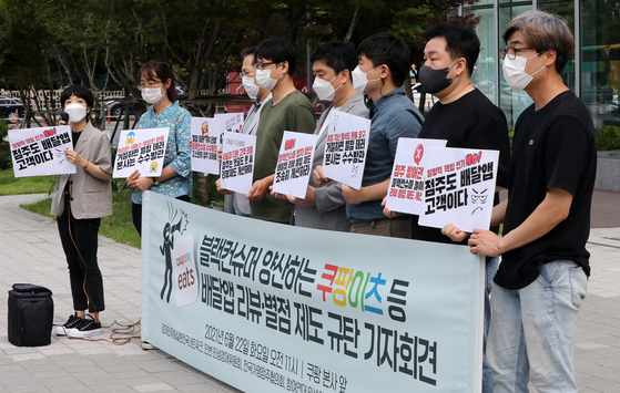 Civic groups and union members hold a press conference in front of Coupang’s headquarters in Songpa District, southern Seoul, on Tuesday, arguing against the review and rating system on the delivery app that results in abuse of power against restaurant owners. [NEWS1]