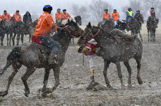 Riders compete during a kok boru, also called ulak tartysh, a traditional game in which players on horseback maneuver with a goat's carcass and score by putting it into the opponents' goal outside Sokuluk village, 12,5 miles west of Bishkek, Kyrgyzstan on March 30. [AP PHOTO/VLADIMIR VORONIN]