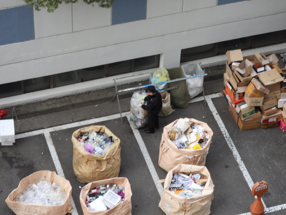 A security guard looks through the recyclable trash collected in an apartment complex in Yeongdeungpo District, western Seoul, on June 19. [KANG CHAN-SU]