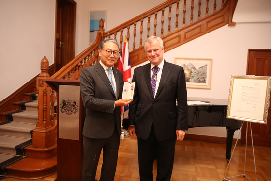 Yun Sang-koo, director of the Rotary Foundation and son of former President Yun Po-sun, left, receives the Order of the British Empire in recognition of services to cultural and educational relations between Britain and Korea at the British Embassy in Seoul on Thursday. Simon Smith, British ambassador to Korea, right, presented the honor. Yun is the eldest son of former President Yun, in whose name an annual conference has been held at the University of Edinburgh on topics pertinent to both Korea and Britain since 2013. The next symposium will be held in Edinburgh in late October 2021, examining the effects of Covid-19 on British and Korean societies. [BRITISH EMBASSY IN SEOUL]
