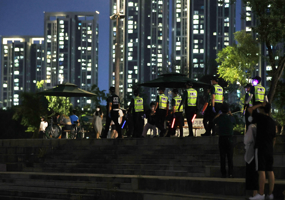 Policemen inspect a park along the Han River in Seoul on Sunday night. Drinking is banned outside in Seoul after 10 p.m. as part of strengthened measures to curb the spread of the coronavirus. [NEWS1]